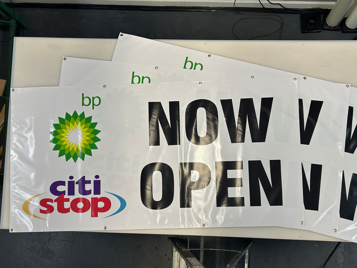 Stack of BP Citi Stop Now Open vinyl banners with grommets