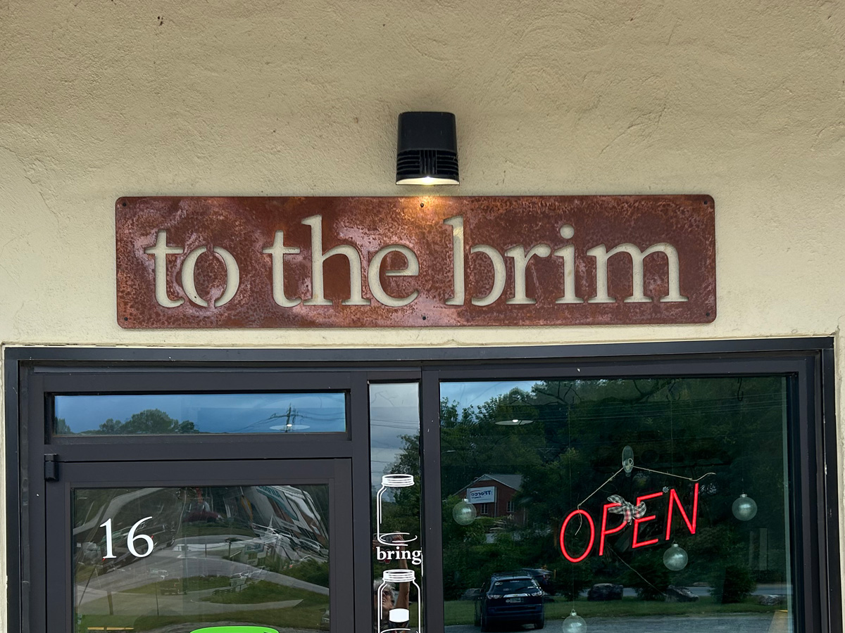 To the brim custom rusted steel storefront sign above entrance in Asheville North Carolina