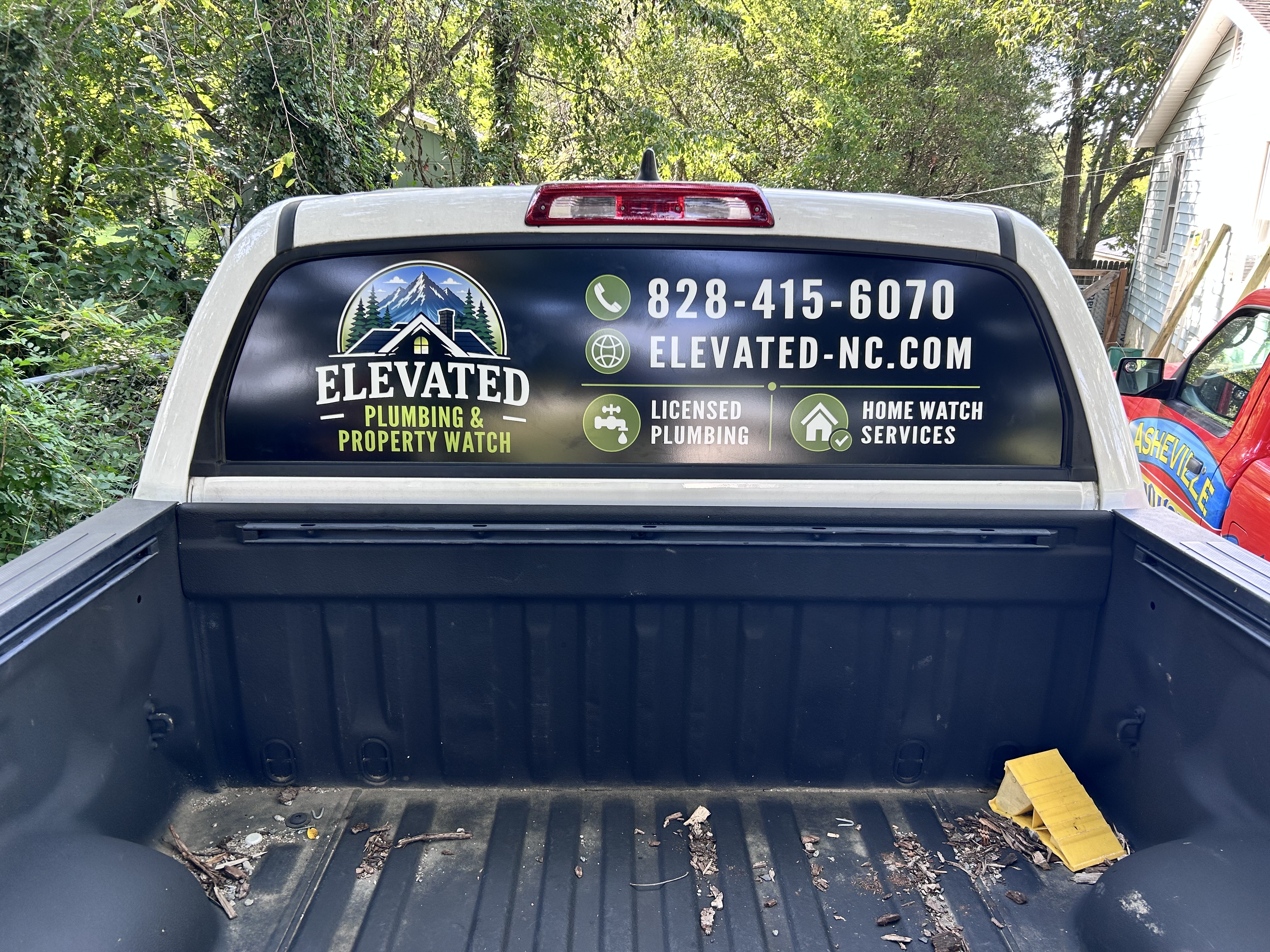 Elevated Plumbing and Property Watch pickup truck with custom rear window graphics