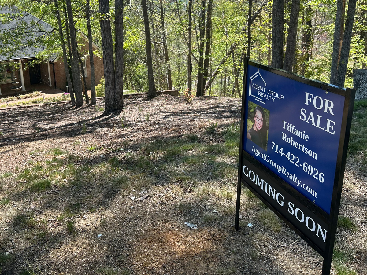 Agent Group Realty real estate sign installed in a black metal property sign frame
