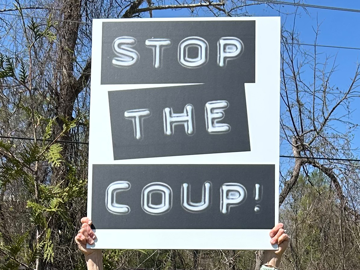 Custom protest sign reading Stop the Coup held outdoors